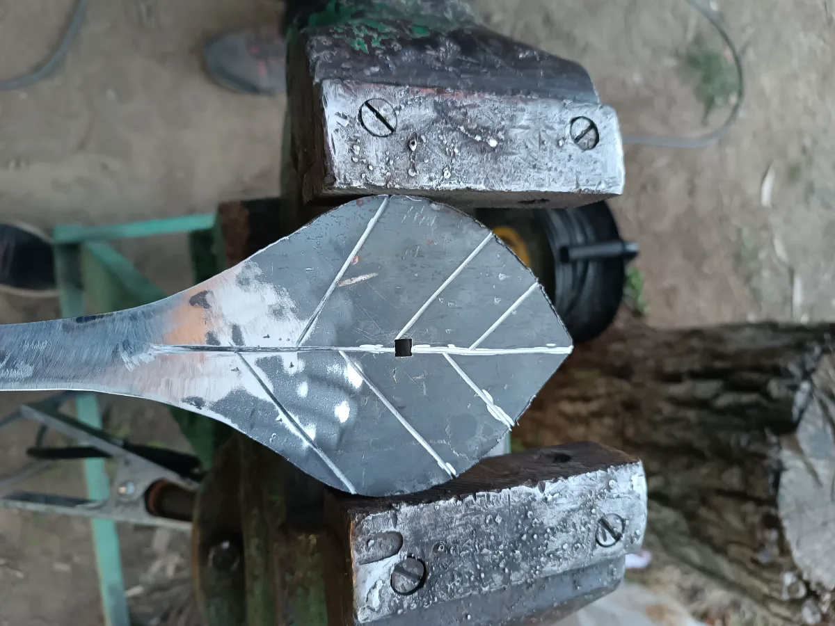 A leaf-shaped sword blade clamped in a vise while being made